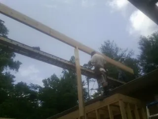 Carpenter setting a ridge beam over a new addition frame — Ice Dam Removal by Roofing Brothers in Harbor View