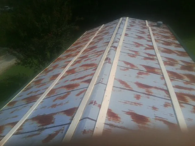 Rusted metal roof panels with new wood purlins before replacement — Storm Damage Roof Repair in Harbor View by Roofing Brothers