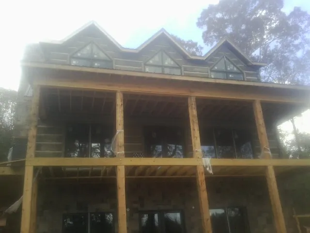 Dormers and porch framing on a large log home under construction — Roof Coating work by our crew in Harbor View