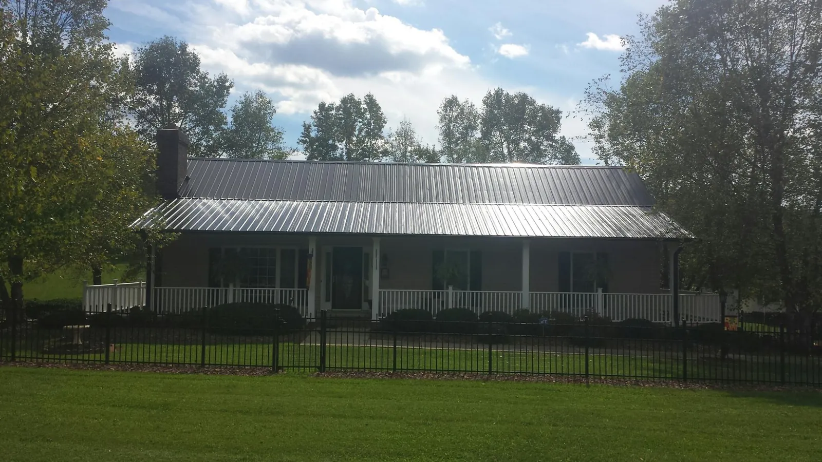 Gray metal roof on a brick ranch with a full width front porch — Gutter Guard Installation work by our crew in Harbor View