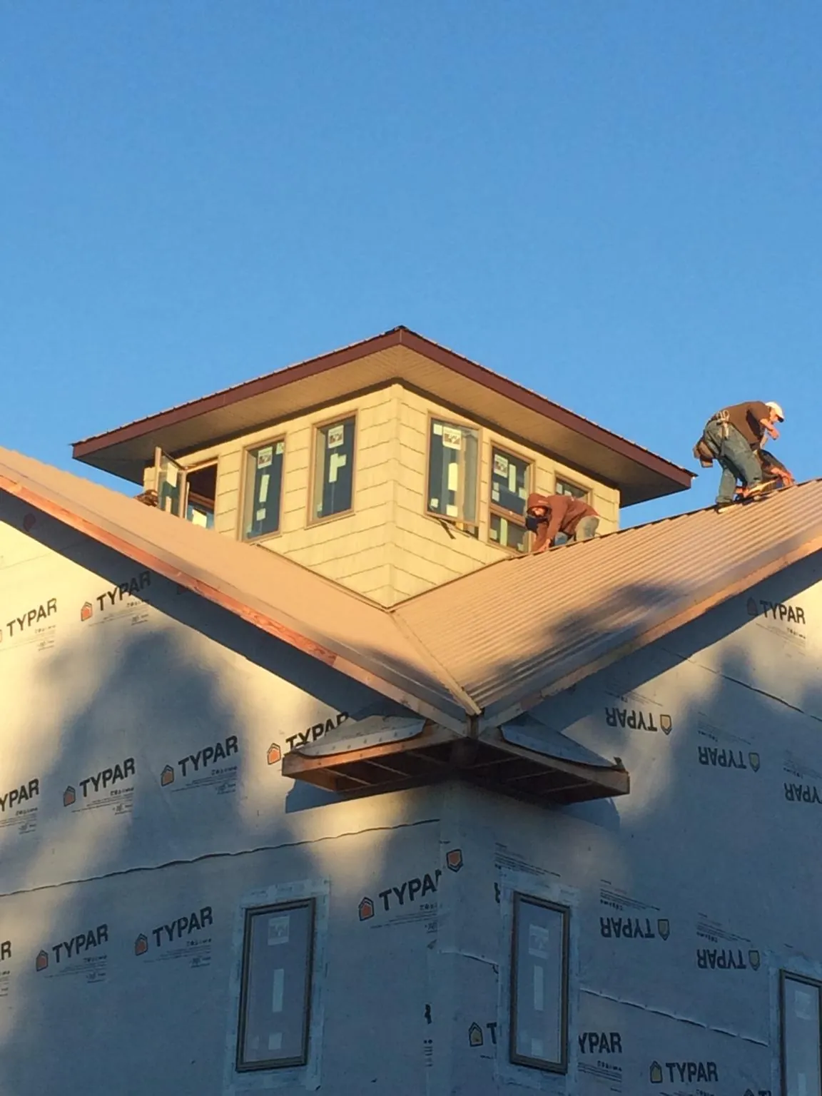 Roofers working around a rooftop cupola on a new metal roof at sunset — Roof Waterproofing in Harbor View by Roofing Brothers